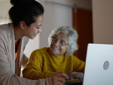Nurse helps senior woman with laptop